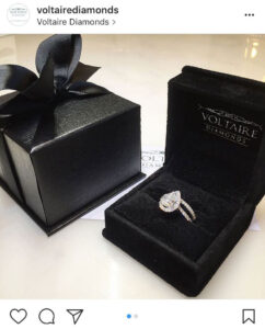 A luxurious diamond engagement ring in a velvet box, presented alongside a charming gift.