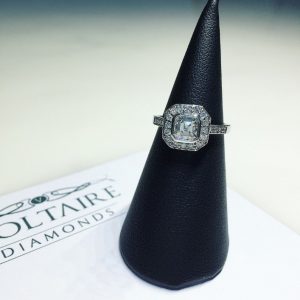 A sparkling geometric-halos diamond engagement ring with geometric-halos resting on a luxurious black velvet stand, highlighting its exquisite design.